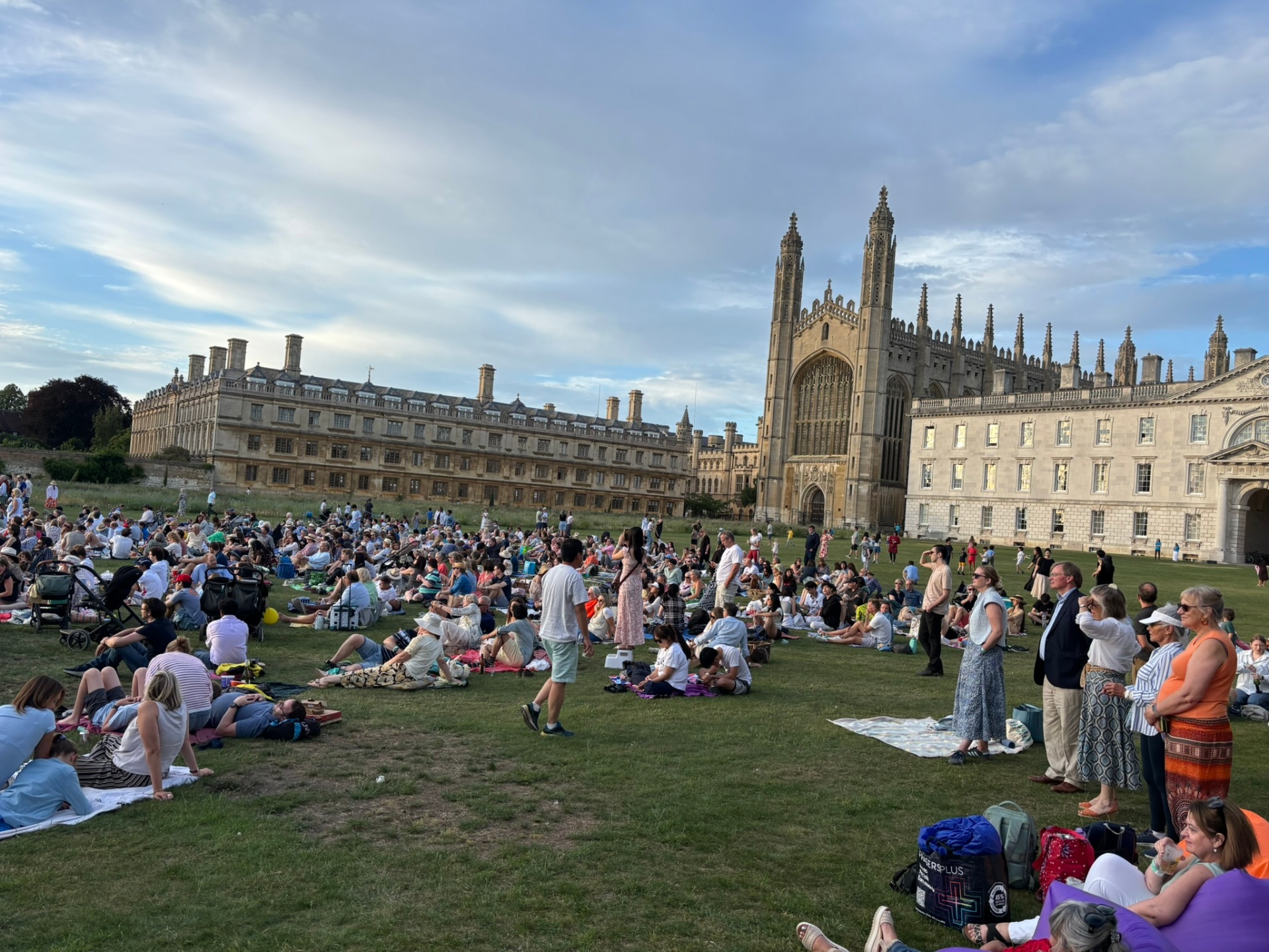 A crowd on the lawn in front of King's College Chapel, Cambridge, at golden hour