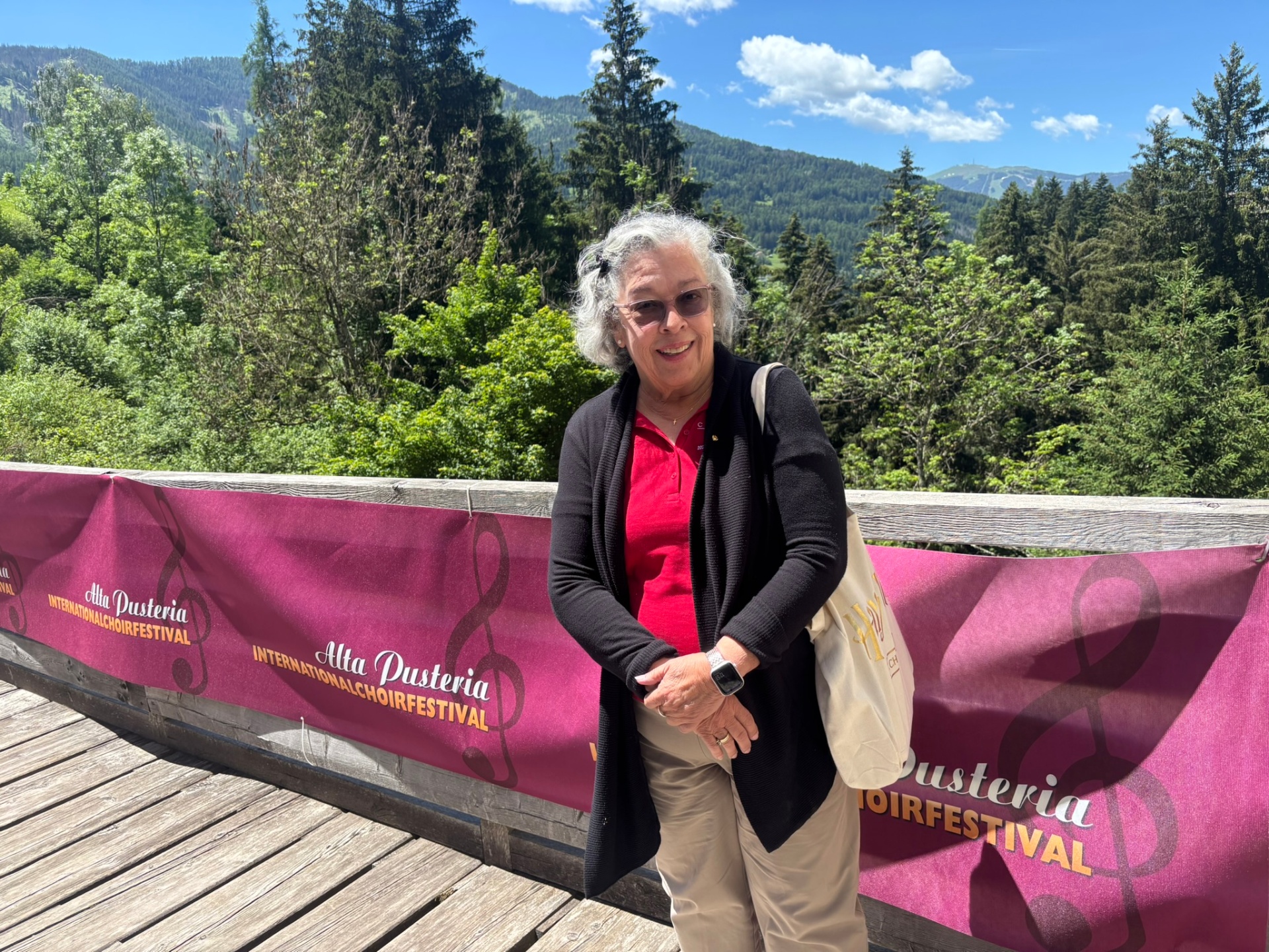 Dr. McGowan standing in front of an Alta Pusteria International Choir Festival banner in the Dolomites